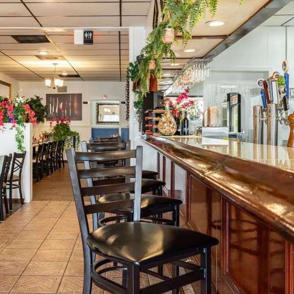 Interior of Djonisi's Restaurant, showing a long wooden bar with stools and dining tables.