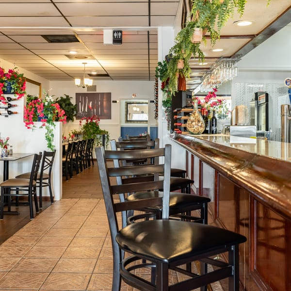 Interior of Djonisi’s Restaurant, showing a long wooden bar with stools and dining tables.